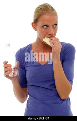 portrait of a young caucasian woman holding a bottle of water and eating a sandwich Stock Photo