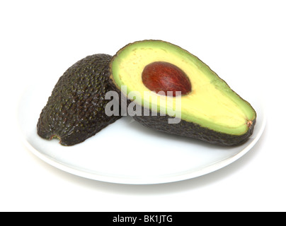 Fresh organic avocado in half on white plate against white background Stock Photo