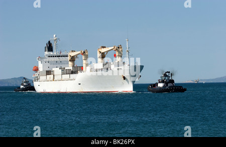 Tug boats guiding a container ship Stock Photo