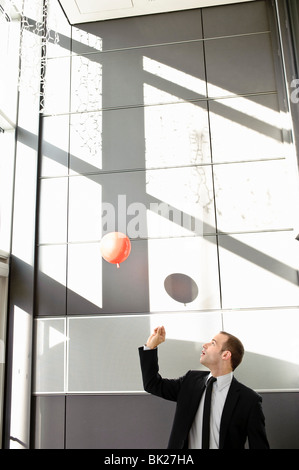 Man setting balloon free in office Stock Photo