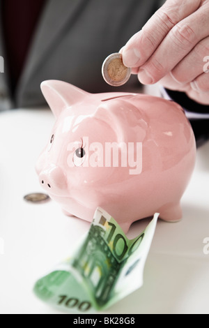 Hand putting coin into piggy bank Stock Photo