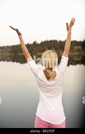 Young woman dancing by lake, stretching Stock Photo