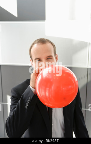 Businessman blowing up red balloon Stock Photo