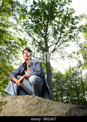 Woman sitting on a rock, in the woods Stock Photo