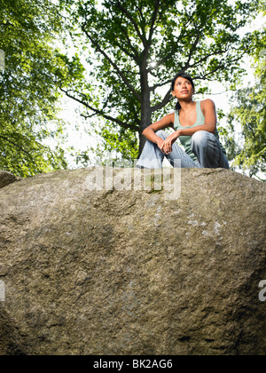 Woman sitting on a rock, in the woods Stock Photo