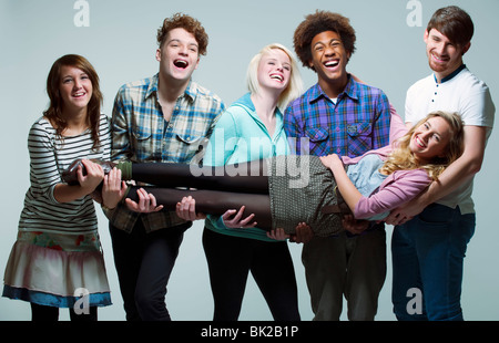 5 young adults carrying young woman Stock Photo