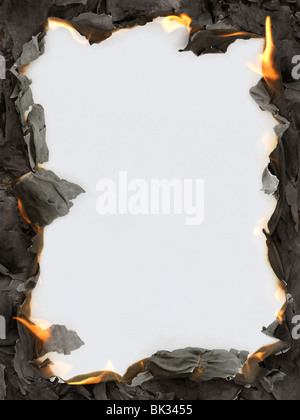 Burning paper ashes revealing blank white background making a frame Stock Photo