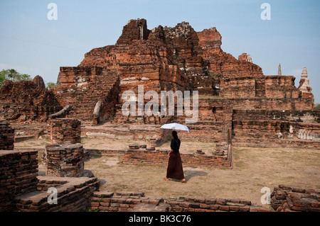 Woman visitor with umbrella at Wat Mahathat Buddhist temple ruins, Ayutthaya, Thailand. Stock Photo