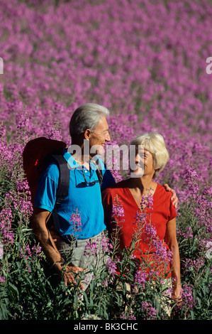 A senior couple out for a hike in a field of purple wildflowers in Albion Basin in the Wasatch Mountains of northern Utah. Stock Photo
