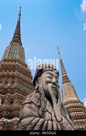 Stone guard statue and chedi at Wat Pho, the Temple of the Reclining Buddha, the largest Buddhist temple in Bangkok Stock Photo