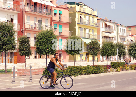 Man riding a bike in Italian resort town Sotomarina (Chioggia) on a street with typical Italian houses Stock Photo