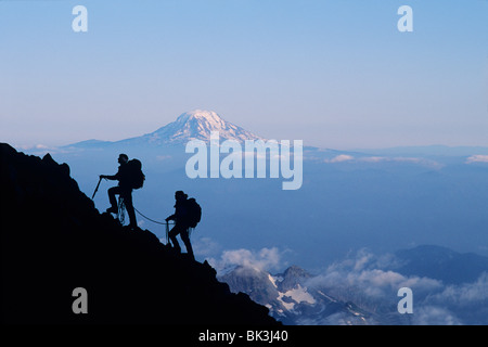 Two climbers ascending Mount Rainier with Mount Adams on horizon, Mount Rainier National Park, Washington. Stock Photo