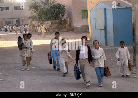 School children walking home from school carrying satchels and briefcases, Egypt Stock Photo