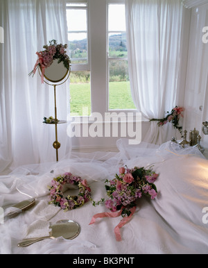 Floral wedding head-dresses and veil on white bed in country bedroom with white voile curtains at the window Stock Photo