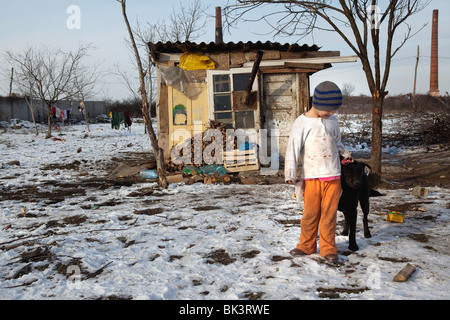 A young girl outside the small hut she shares with her family in a Roma community within Arad, Romania. Stock Photo