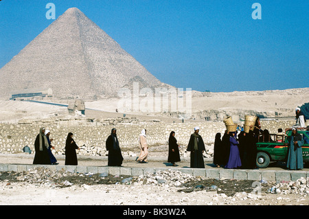 Egyptians walking near the Sphinx and the Great Pyramid of Cheops in Giza, Egypt Stock Photo