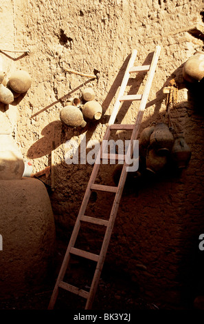 Ceramic pots hanging on an adobe wall, and wooden ladder, Morocco Stock Photo