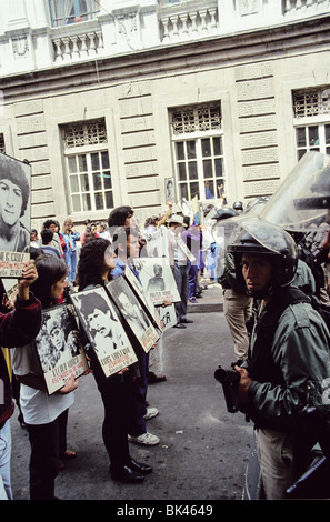 Protesters with signs & images of people who had been murdered or who had disappeared confronting riot police with teargas Stock Photo