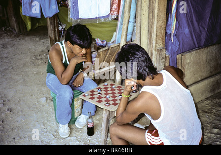 Young adults playing checkers using bottle caps for game pieces, Guatemala Stock Photo