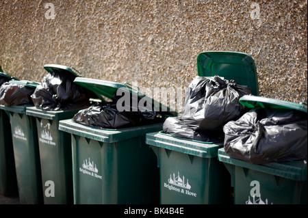 Overflowing Domestic Wheelie Bins against a wall in Brighton and Hove, UK Stock Photo
