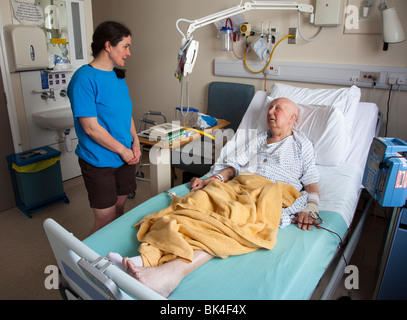 Patient in hospital bed with visitor Wales UK Stock Photo