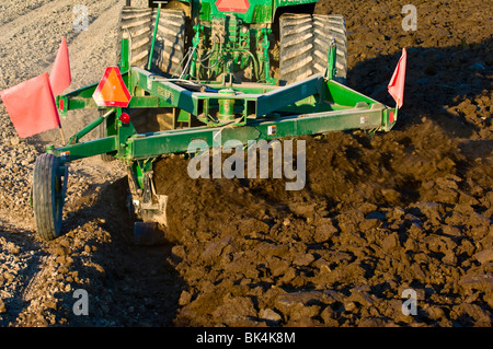 John Deere tractor plowing with reversible plow to prepare the field for planting in the spring in Skagit County, Washington Stock Photo