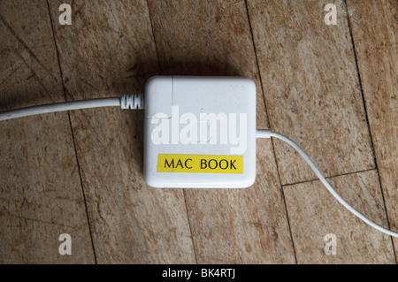 An Apple Mac Book power supply on a wooden dining room floor, UK. Stock Photo