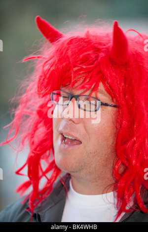 A man wearing a red wig and devil horns in Jindabyne, Australia. Stock Photo