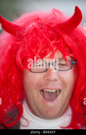 A man wearing a red wig and devil horns in Jindabyne, Australia. Stock Photo