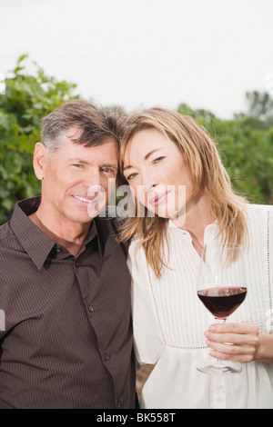 Portrait of Couple in Vineyard Holding a Glass of Wine Stock Photo