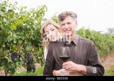 Portrait of Couple in Vineyard Holding a Glass of Wine Stock Photo