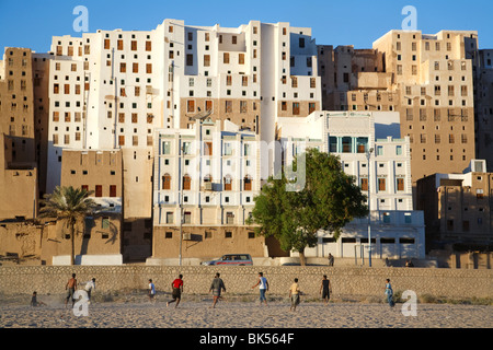 Young people play football (soccer) in a UNESCO listed heritage town of Shibam, Yemen famous for its muddy tall buildings. Stock Photo