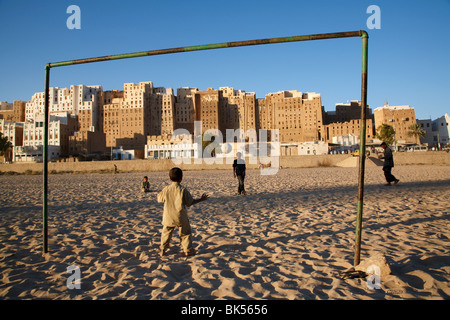 Children play football (soccer) in a UNESCO listed heritage town of Shibam, Yemen famous for its muddy tall buildings. Stock Photo
