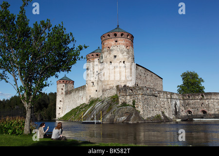 Girls relaxing beside Olavinlinna Medieval Castle, Savonlinna, Saimaa Lake District, Savonia, Finland Stock Photo