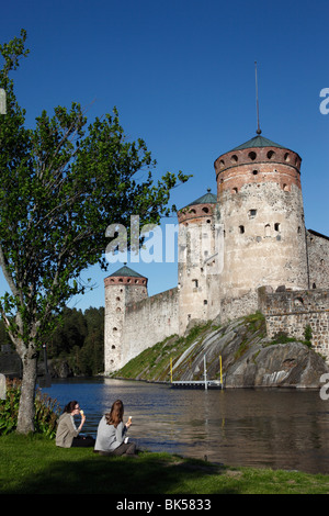 Girls relaxing beside Olavinlinna Medieval Castle (St. Olaf's Castle), Savonlinna, Savonia, Finland, Scandinavia, Europe Stock Photo