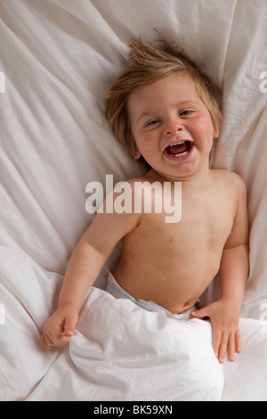 Happy toddler laying on bed Stock Photo