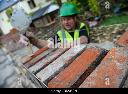 Building of a garden wall with Cotswold stone and reclaimed red bricks UK Stock Photo