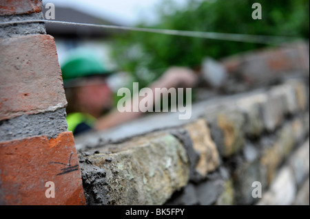 Building of a garden wall with Cotswold stone and reclaimed red bricks UK Stock Photo