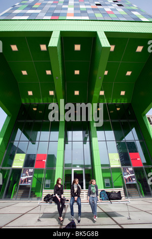 Three students on swing bench in front of modern building at Utrecht University in The Netherlands Stock Photo
