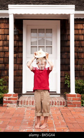 Boy on sidewalk playing with seashell Stock Photo