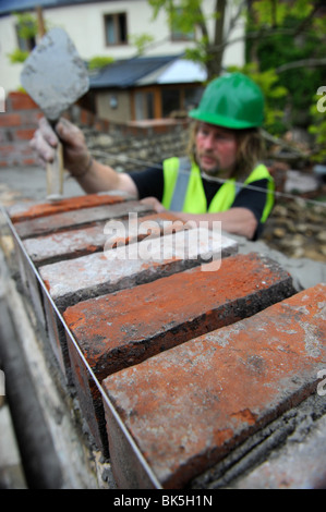 Building of a garden wall with Cotswold stone and reclaimed red bricks UK Stock Photo