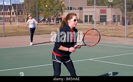 High school girls on a tennis team play a match on a sunny spring afternoon Stock Photo