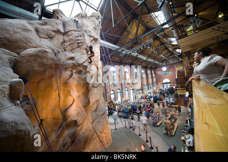 Inside the Denver R.E.I. sports goods and outdoors camping equipment store. A little girl climbs the indoor rock wall. Stock Photo