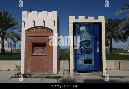 An old, not functioning potable water dispenser next to a modern mineral water dispenser in Doha, Qatar. Stock Photo