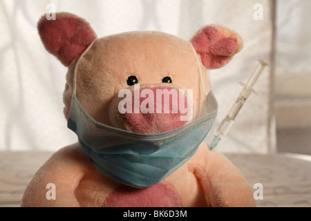 Toy pig with a syringe in the shoulder, head shot. Stock Photo