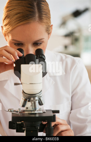 female scientist looking through microscope and doing research in lab Stock Photo