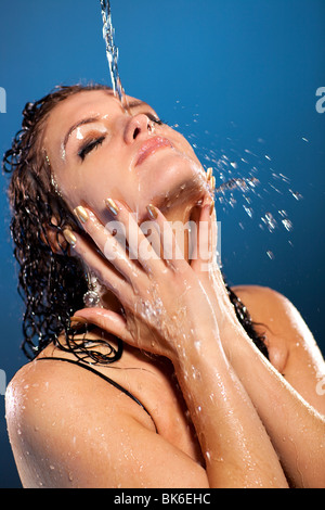 Water flowing on woman face. On blue background. Stock Photo