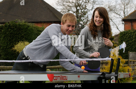 Teenagers playing a game of table tennis in their garden Stock Photo