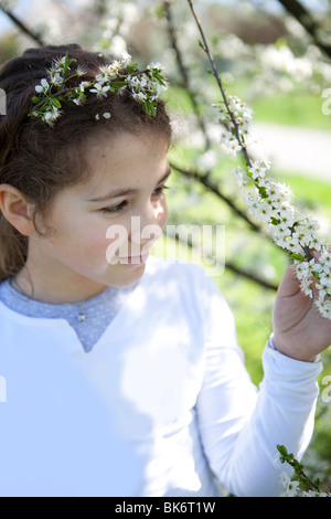 Pretty little girl touching a cherry tree blossoms