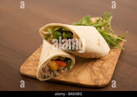 Tuna Salad Wrap Sandwich ideal for a lunch or snack when hungry. The wrap contains peppers, tuna and lettuce in a tortilla on a wooden board. Stock Photo